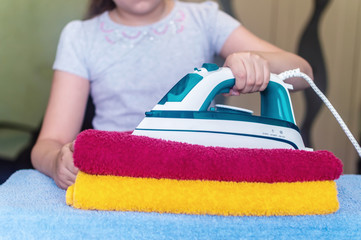 iron in the hand of the girl on the Ironing Board irons and steams clothes