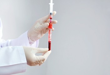 Female doctor's hand in white coat and medical glove handling a blood probe for testing in...