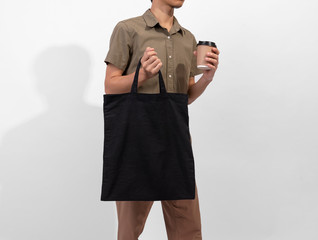 Man is holding black bag canvas fabric for mockup blank template isolated on gray background.