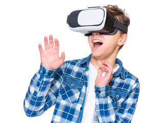Amazed teen boy wearing virtual reality goggles watching movies or playing video games, on white. Surprised teenager looking in VR glasses. Child experiencing 3D gadget technology.