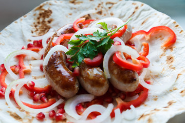 Fried pork sausages on pita bread with ketchup and Armenian appetizer Aivar with vegetables. Lavash, red bell pepper, onions, sausages. Oktoberfest food, the concept of the pub