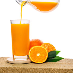 pouring orange juice in glass with fruits on stone isolated on white background, concept of healthy lifestyle