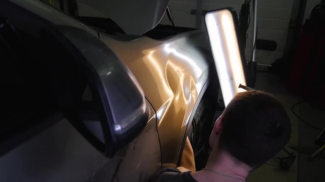 Paintless Dent Repair Removal. Tap Down Tools Dent Rubber Hammer Auto Body. The guy knocks with a hammer on the car to align the dent on technology PDR.