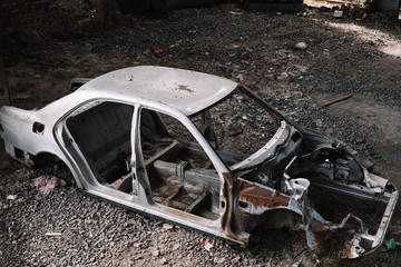 Fototapeta na wymiar battered and rusty gray car body in a landfill