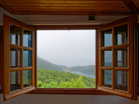 wooden window frame with view to a mountain lake, misty fall weather