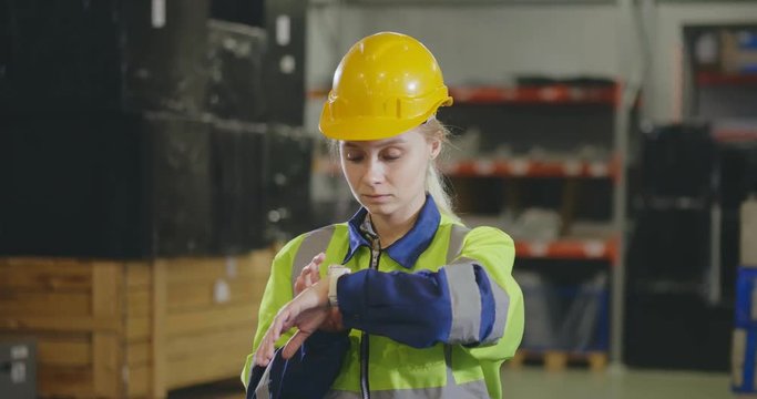 Portrait of young female engineer waiting for her boyfriend in warehouse. Factory worker surprising his girlfriend. Relationship at work