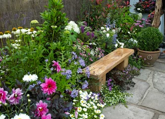 A traditional thatched cottage garden designed to creat a calming and relaxing space with colourful flowers and seating © Garden Guru