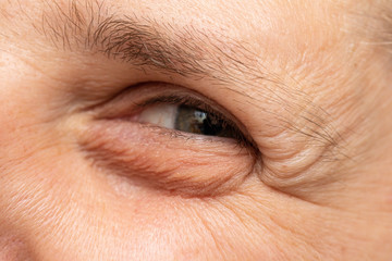 A close-up view on the eye of a young Caucasian male with green eyes. Happy guy with crow’s feet,...