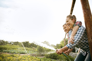 Young and happy farmer's couple at their garden in sunny day. Man and woman engaged in the...