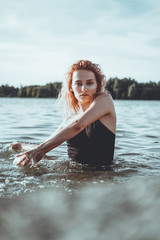 Young beautiful woman standing in the water. Black swimsuit. Vintage style. vertical photo