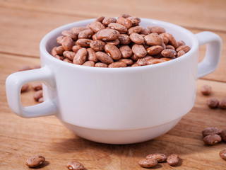 Close Up brown pinto beans in the bowl on wooden background.