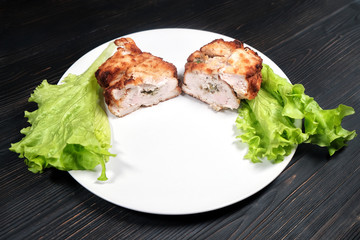 Two halves chicken cutlet in restaurant menu. Chop stuffed in breadcrumbs with lettuce leaves. Cutlet on a plate in the restaurant.