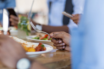leisure, food and people concept - close up of african american man eating with friends at restaurant