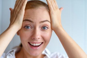 Emotion Concept. Woman standing isolated on white holding head smiling happy illuminated with solution close-up