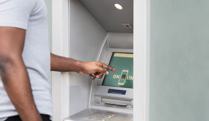 Side view of african man touching screen on ATM