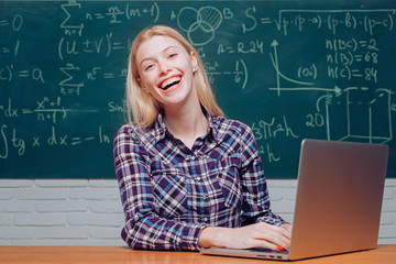 Teenage students with school notebook. Woman working on laptop computer over chalkboard background. Student studying at home. Science.