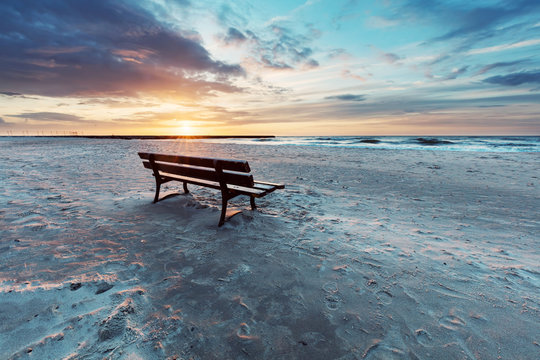 Lonely bench on the beach at sunset with view on the sea