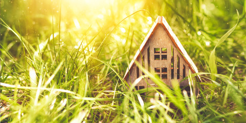 Fototapeta na wymiar Eco house concept, wooden house from natural organic materials in green grass and sun rays long banner