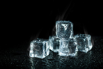 ice cubes and cooling smoke on dark table background. Ice blocks with cold drinks.