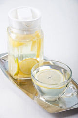   Lemon water in a glass jug and in a glass cup