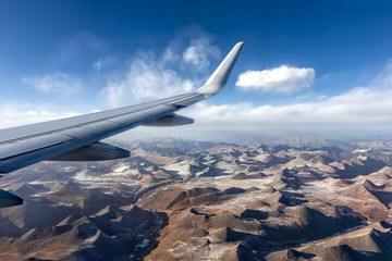 Obraz premium Wing of an airplane with the Himalayas below with its snow topped peaks