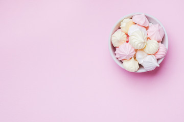 Fototapeta na wymiar Colored small meringues on a pink background. Flat lay concept. Copy space.