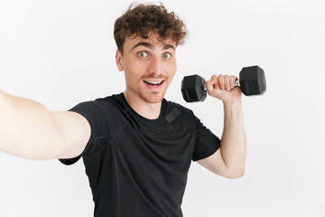 Fototapeta na wymiar Photo closeup of handsome sporty man in t-shirt looking at camera and taking selfie photo while holding dumbbell