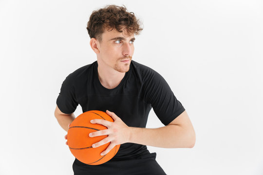 Photo closeup of concentrated young man in t-shirt holding and throwing ball while playing basketball game