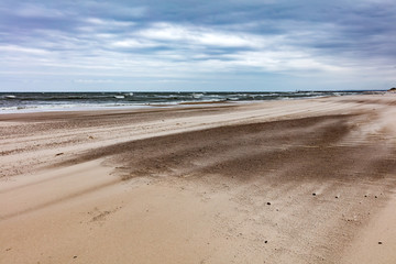 Sandy beach on stormy day by the sea.