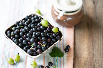 Blackcurrants in the ceramic bowl on a wooden table
