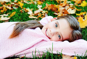 Autumn portrait of adorable smiling  little girl child lying in leaves