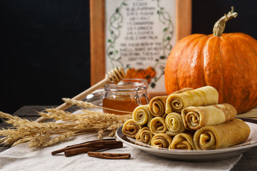 Pumpkin crepes with honey and cinnamon on a wooden table.