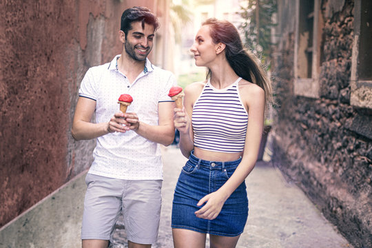 Couple Of Young People Walking While They're Eating An Ice Cream In The Old City Center..