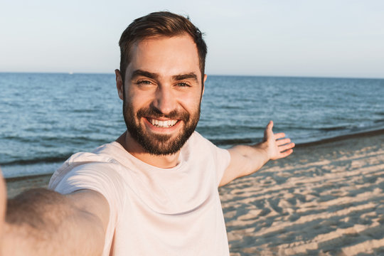 Handsome cheerful man standing at the beach