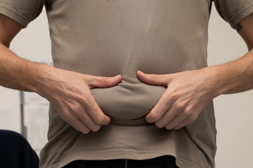 A thirty something year old Caucasian male is seen close up. Holding the extra roll of fat around...