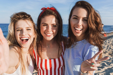 Three happy girlfriends spending fun time at the beach