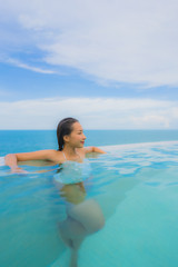 Fototapeta na wymiar Portrait young asian woman relax smile happy around outdoor swimming pool in hotel resort with sea ocean view