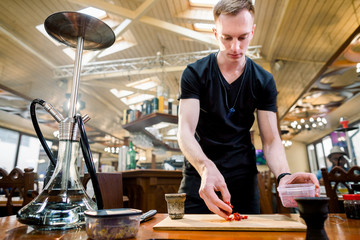Hookah in the process preparations. The bartender prepares the tobacco to ignite.