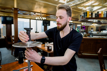 Preparing the shisha, aka nargile or hookah at a restaurant by placing the cup on top