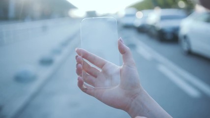 Future technology, business concept. Close-up human holding a smartphone scrolling and tapping on transparent touchscreen outdoors in empty street. - Powered by Adobe