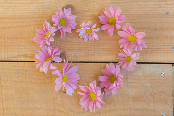 Beautiful flowers in heart shape on wooden background