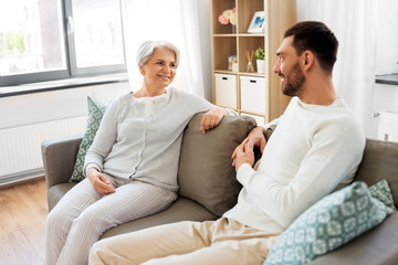 family, generation and people concept - happy smiling senior mother talking to adult son at home