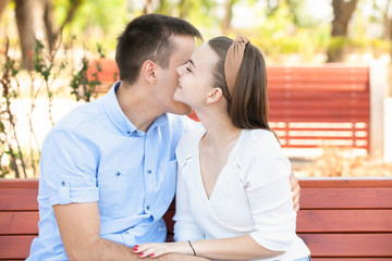 Obraz premium Young couple sitting on bench in park.
