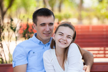 Fototapeta premium Young couple sitting on bench in park.