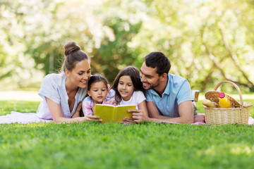 family, leisure and people concept - happy mother, father and two daughters laying on picnic...