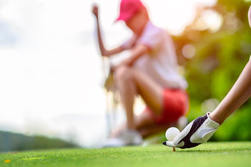 hand of young woman golf player holding golf ball laying on wooden tee, prepare and ready to hit...
