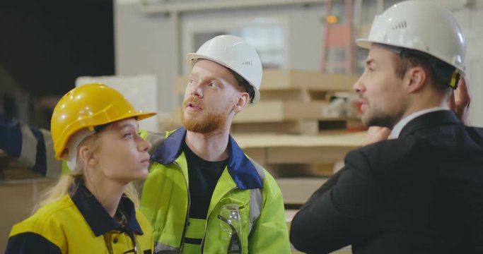 Factory workers talking to mature engineer