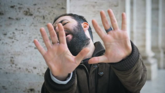 Funny latin young man making refusal gesture at camera.Fun, jokes-outdoor