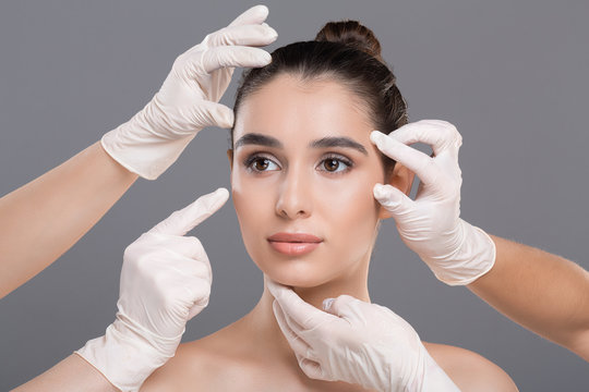 Doctor's Hands In Gloves Touching Face Of Young Beautiful Woman