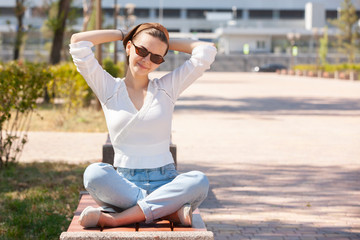 Fototapeta na wymiar Young beautiful woman sitting on bench in park.